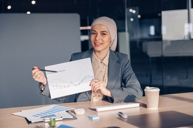 Smiling Muslim Businesswoman In Hijab Shows A Grap AMH74W7 768x512